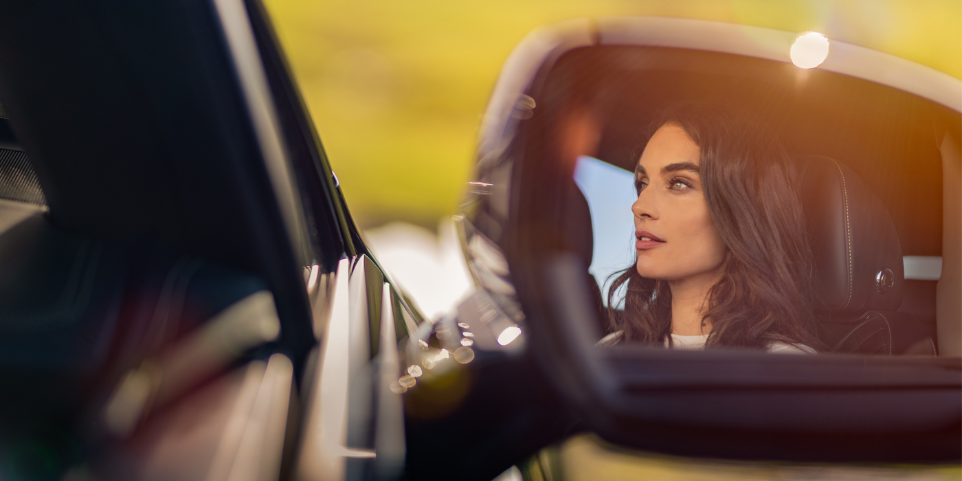 Bentley Johannesburg profile of dark haired woman's face in mirror of Bentley car in sunlight