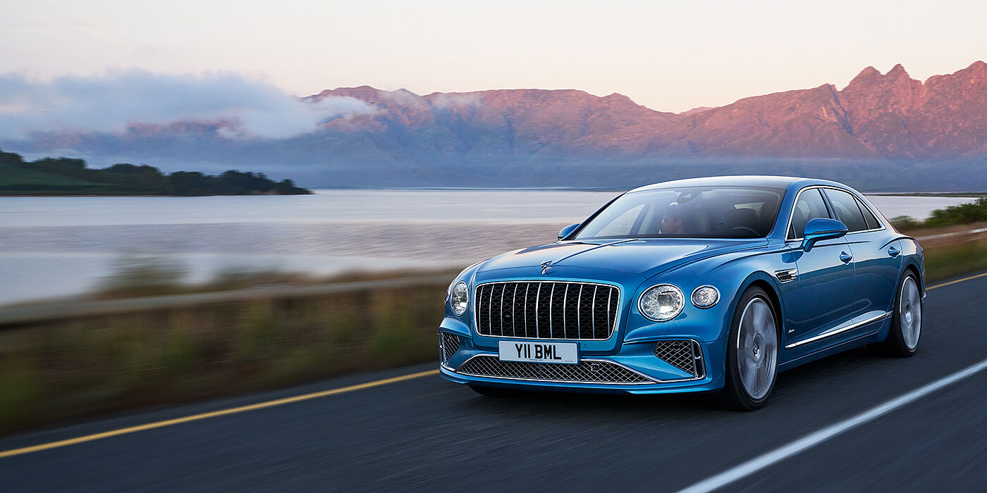 Bentley Johannesburg New Bentley Flying Spur Azure sedan in Light windsor blue paint by Mulliner, with 22 inch Azure wheels and chrome straight vaned grille driving on a mountain road