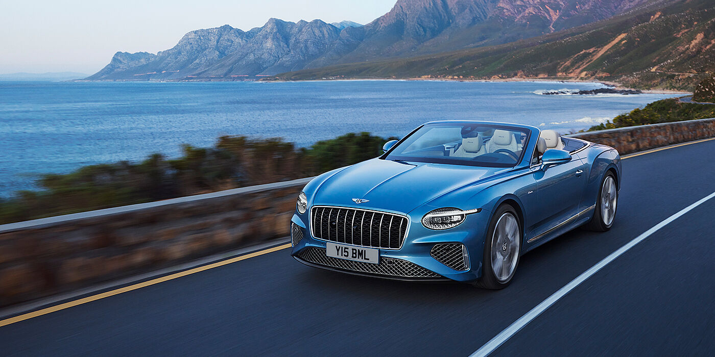 Bentley Johannesburg New Bentley Continental GTC Azure convertible in Light Windsor blue paint with 22 inch Azure wheels and chrome grill, driving dynamically by the sea