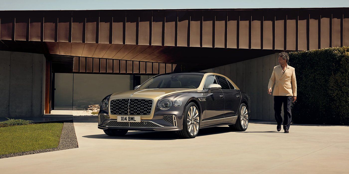 Bentley Johannesburg Bentley New Flying Spur Mulliner V8 hybrid sedan front three quarters in Rose Gold over Magnetic paint, parked near modern home