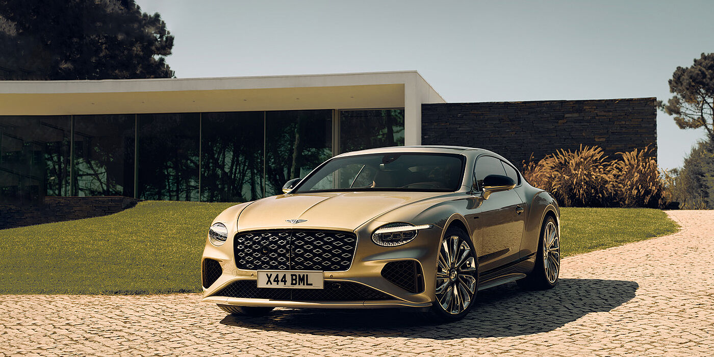 Bentley Johannesburg Bentley Continental GT Mulliner coupe front three quarters in Patina paint parked outside a glass fronted building with a grass lawn behind it
