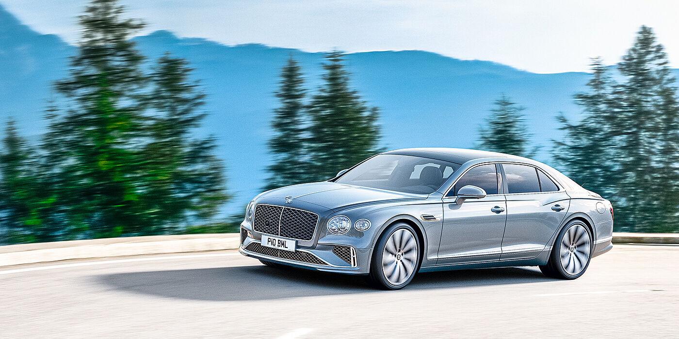 Bentley Johannesburg New Bentley Flying Spur sedan side view in Silverlake paint with ten spoke wheels and chrome matrix grille driving dynamically on a mountain road