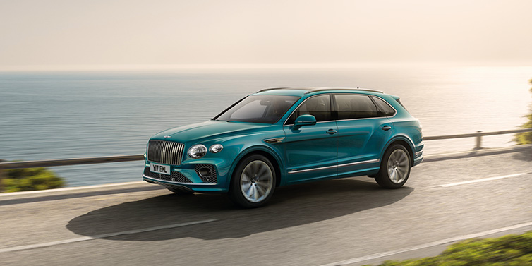 Bentley Johannesburg Bentley Bentayga Extended Wheelbase Azure SUV in Topaz blue paint driving dynamically by the ocean