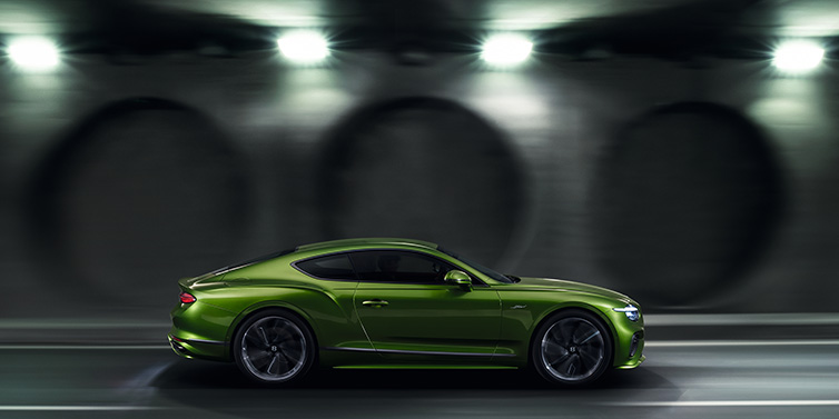 Bentley Johannesburg Bentley Continental GT Speed coupe profile in Tourmaline Green driving dynamically past a concrete wall at night