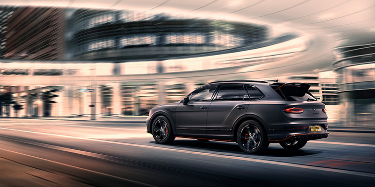 Bentley Johannesburg Bentley Bentayga S Black Edition SUV rear three quarter in Anthracite Satin paint driving dynamically through a city at night