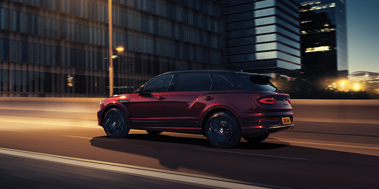 Bentley Johannesburg Bentley Bentayga Extended Wheelbase Mulliner SUV in Cricket Ball red paint driving dynamically in city at night