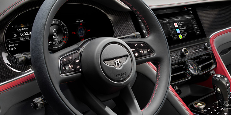 Bentley Johannesburg Bentley Flying Spur Speed sedan front interior detail showing steering wheel and driver screens surrounded with Hotspur red and Gravity Grey hides